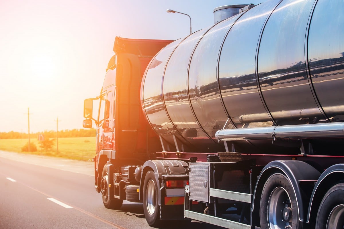 Illustrative photograph of a polished steel tanker trailer travelling on a highway.